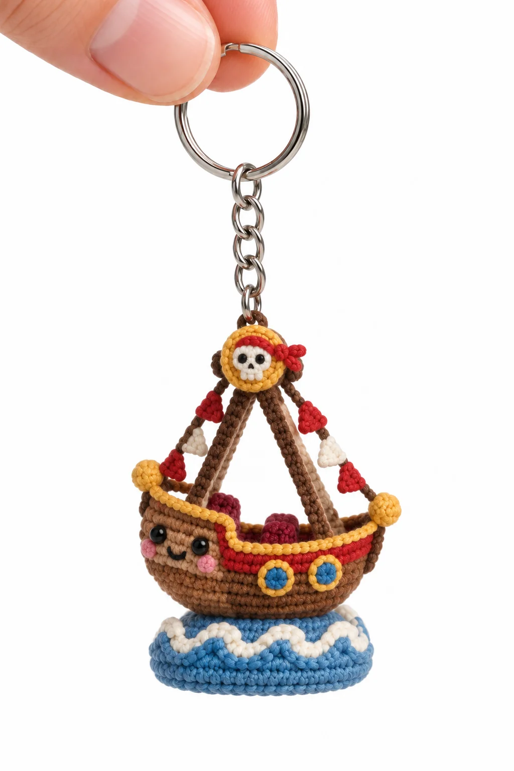 Brown crochet pirate ship swing ride keychain with skull flag, red triangular sails and a blue wave base