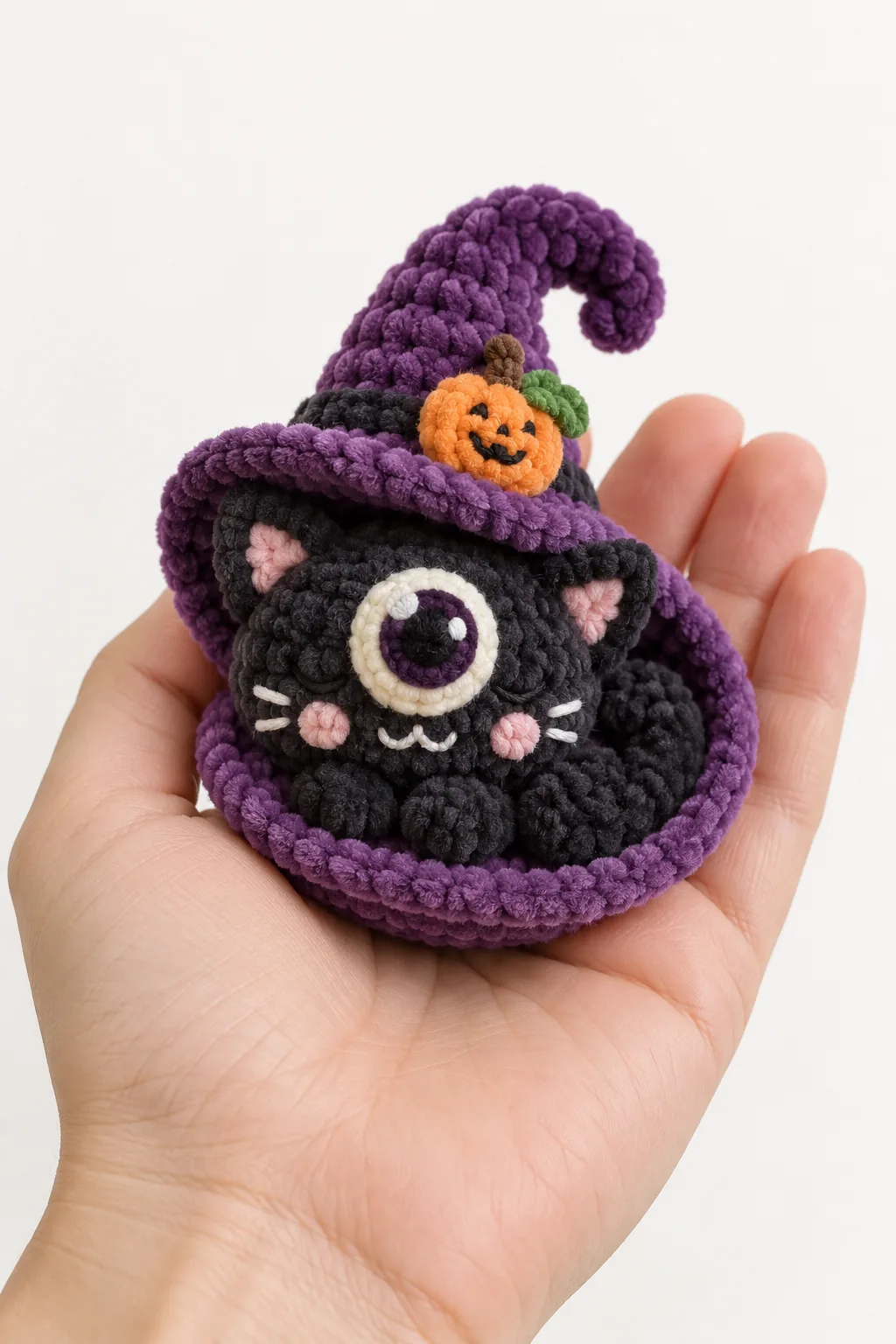 One-eyed black cat in a purple witch hat crochet Halloween plush