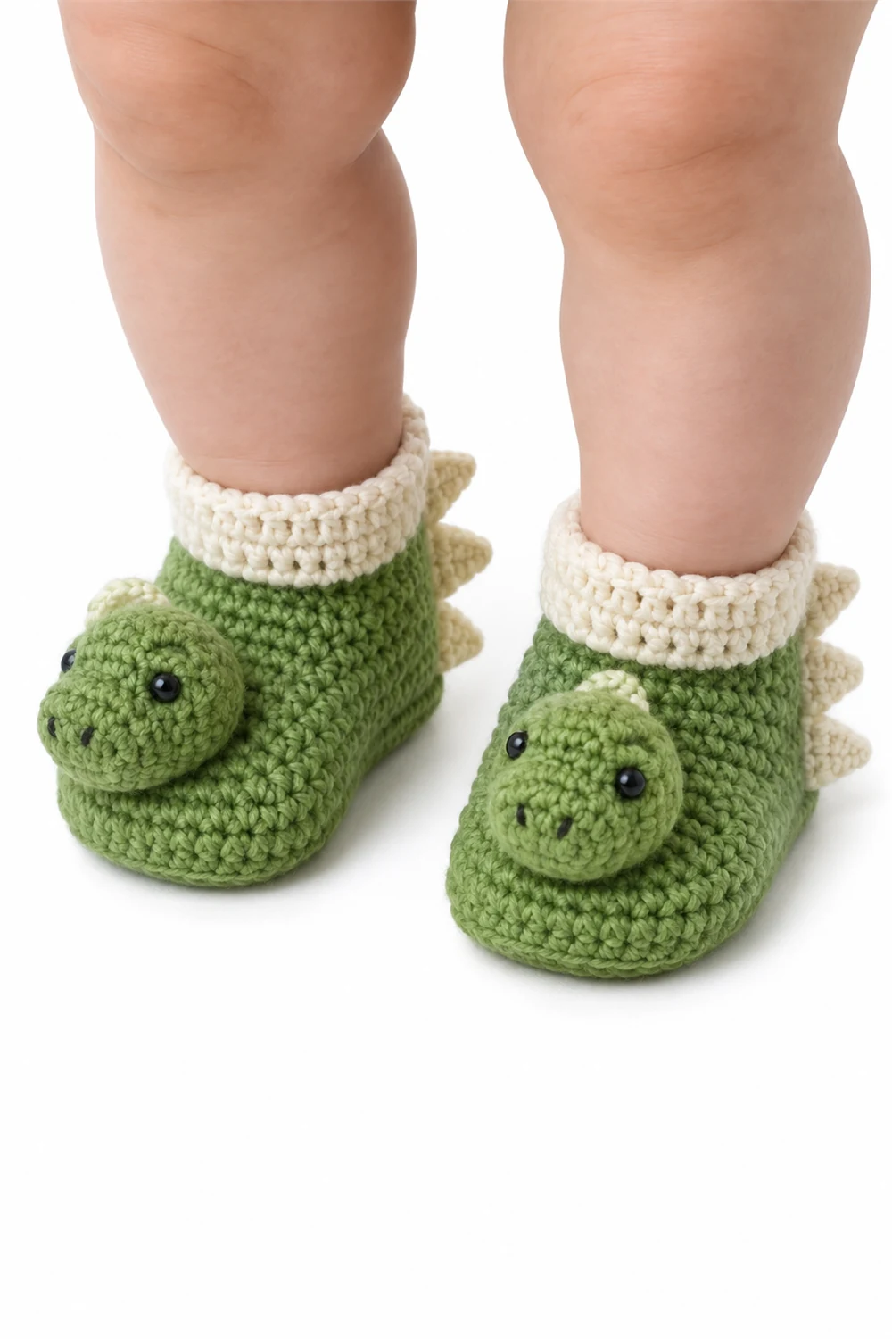 Green crochet baby booties featuring a friendly dinosaur motif