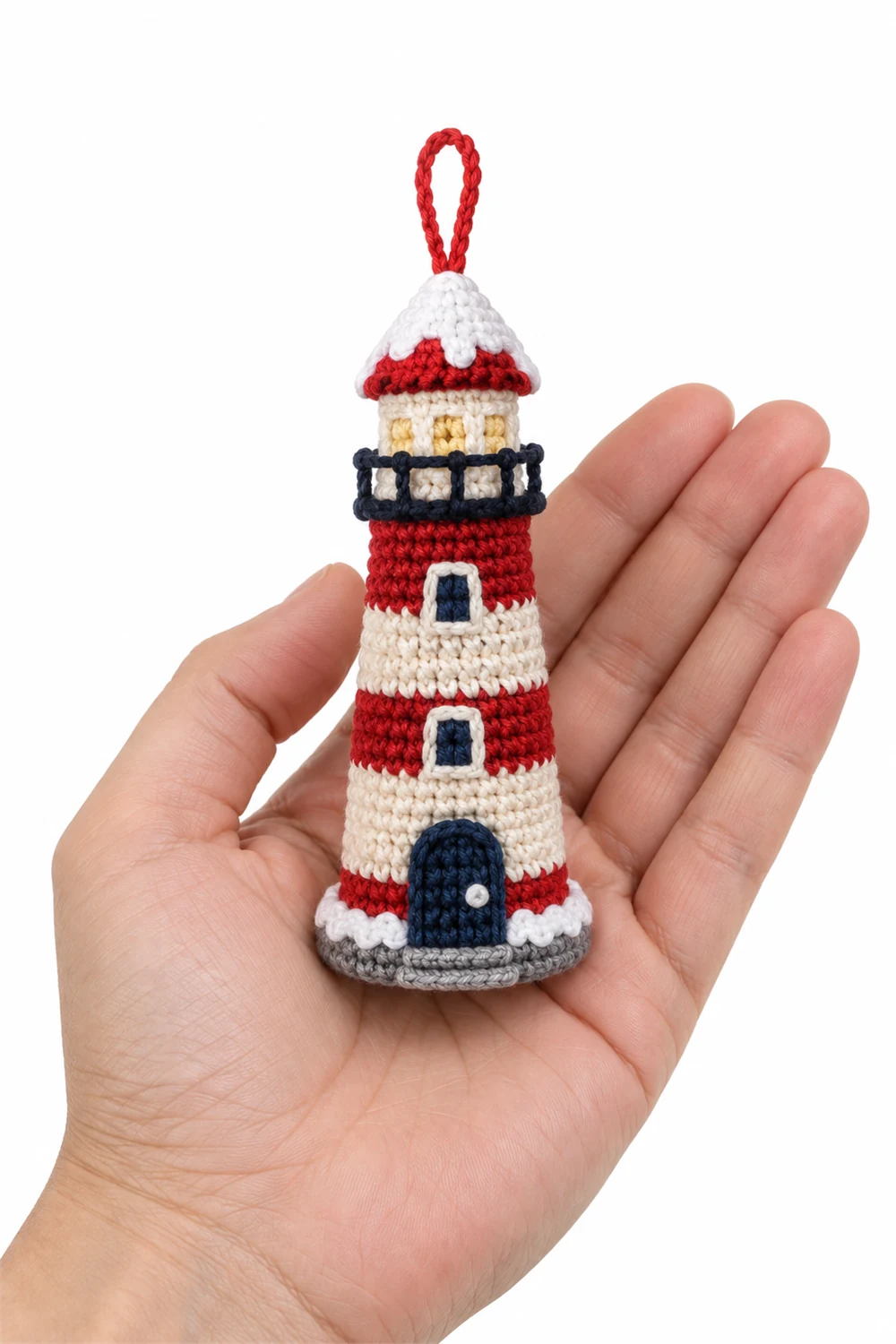 Striped crochet lighthouse ornament with snow at its base